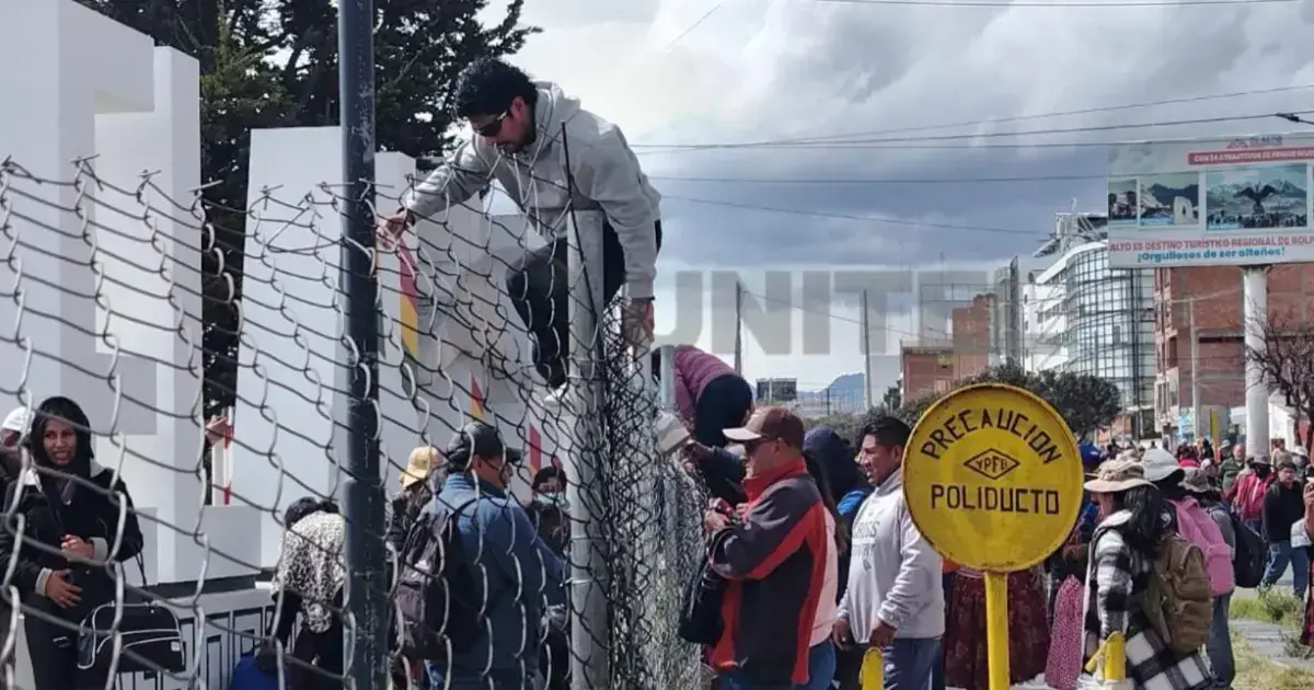 Personas trepan las rejas del perímetro del aeropuerto de El Alto para no perder su vuelo.
