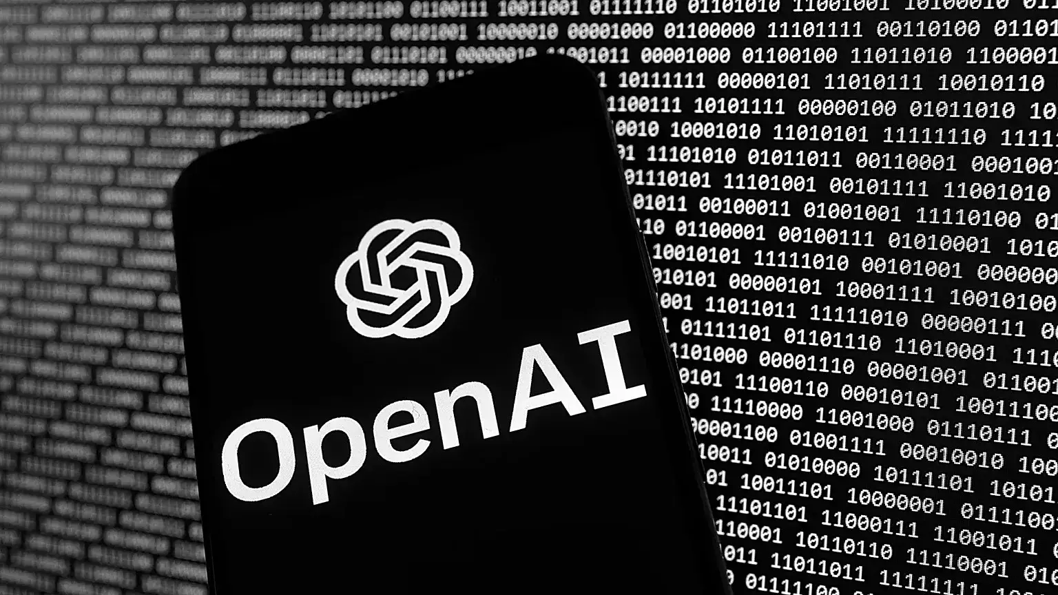 El logotipo de OpenAI aparece en un teléfono móvil frente a una pantalla de ordenador con datos binarios aleatorios.