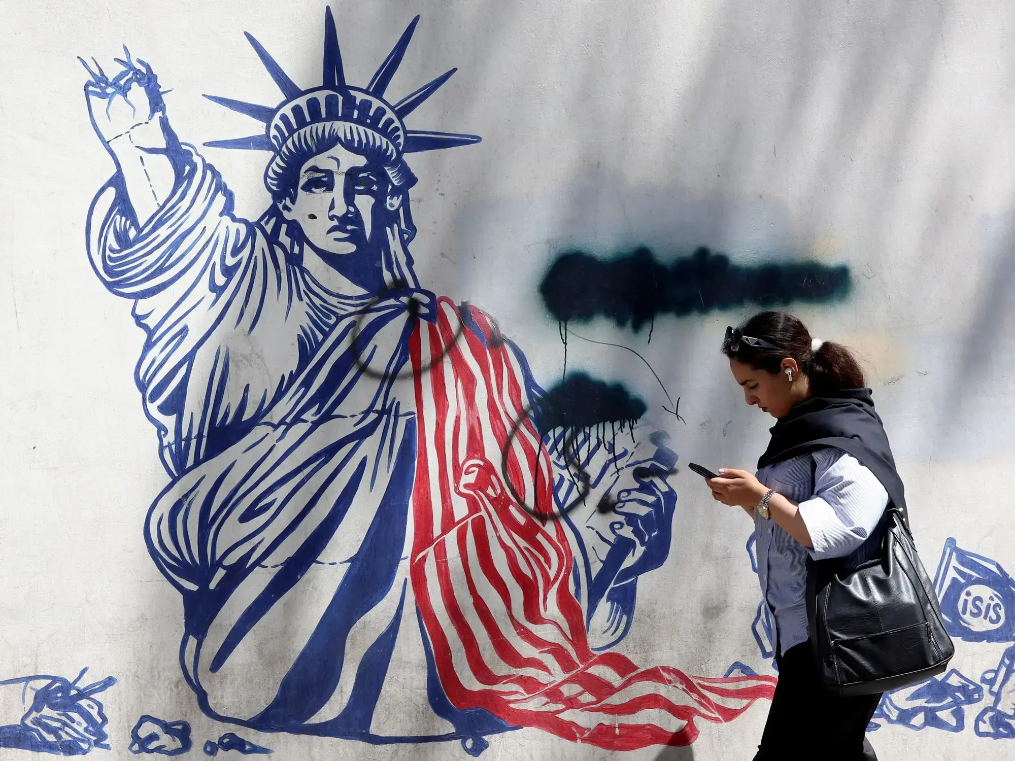 Una iraní camina junto a un mural antiestadounidense cerca de la antigua Embajada de Estados Unidos en Teherán.