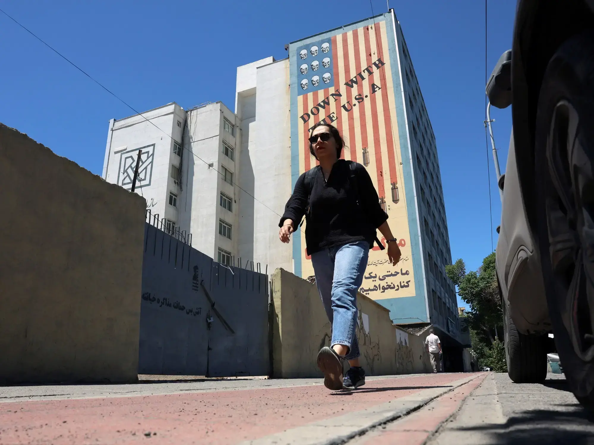 Una iraní camina en Teherán con un mural antiestadounidense de fondo.