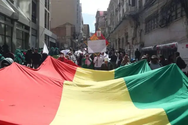 Personas ondean una bandera de Bolivia durante una marcha para exigir al gobierno soluciones ante los bloqueos y el desabaste