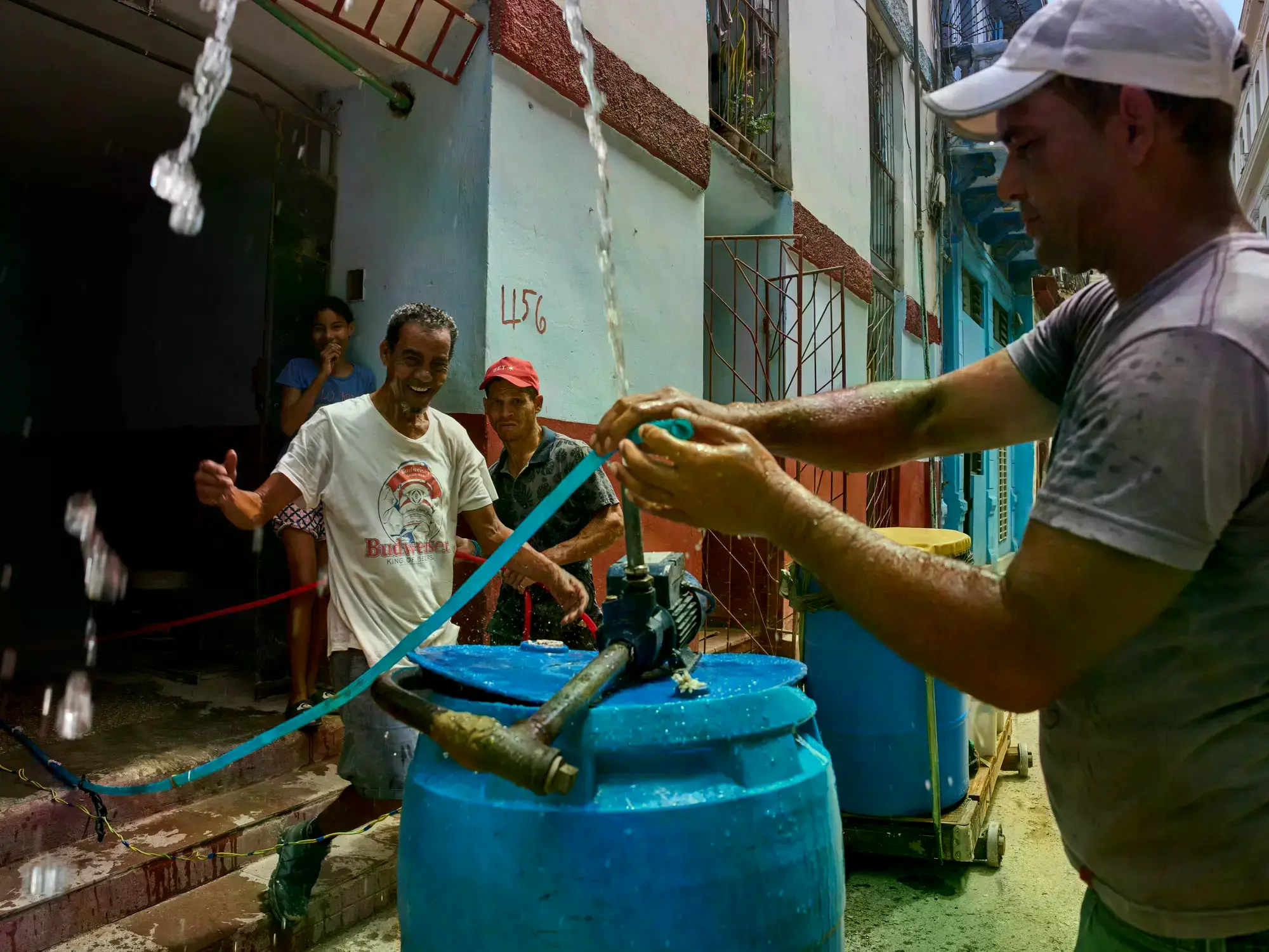 Varias personas reaccionan cuando un vecino coloca un motor en un recipiente con agua a la entrada de su edificio en La Haban