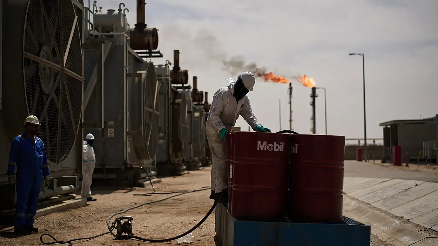 Un peón recoge aceite de motor mientras trabaja en la estación de desgasificación del yacimiento petrolífero de Zubair.