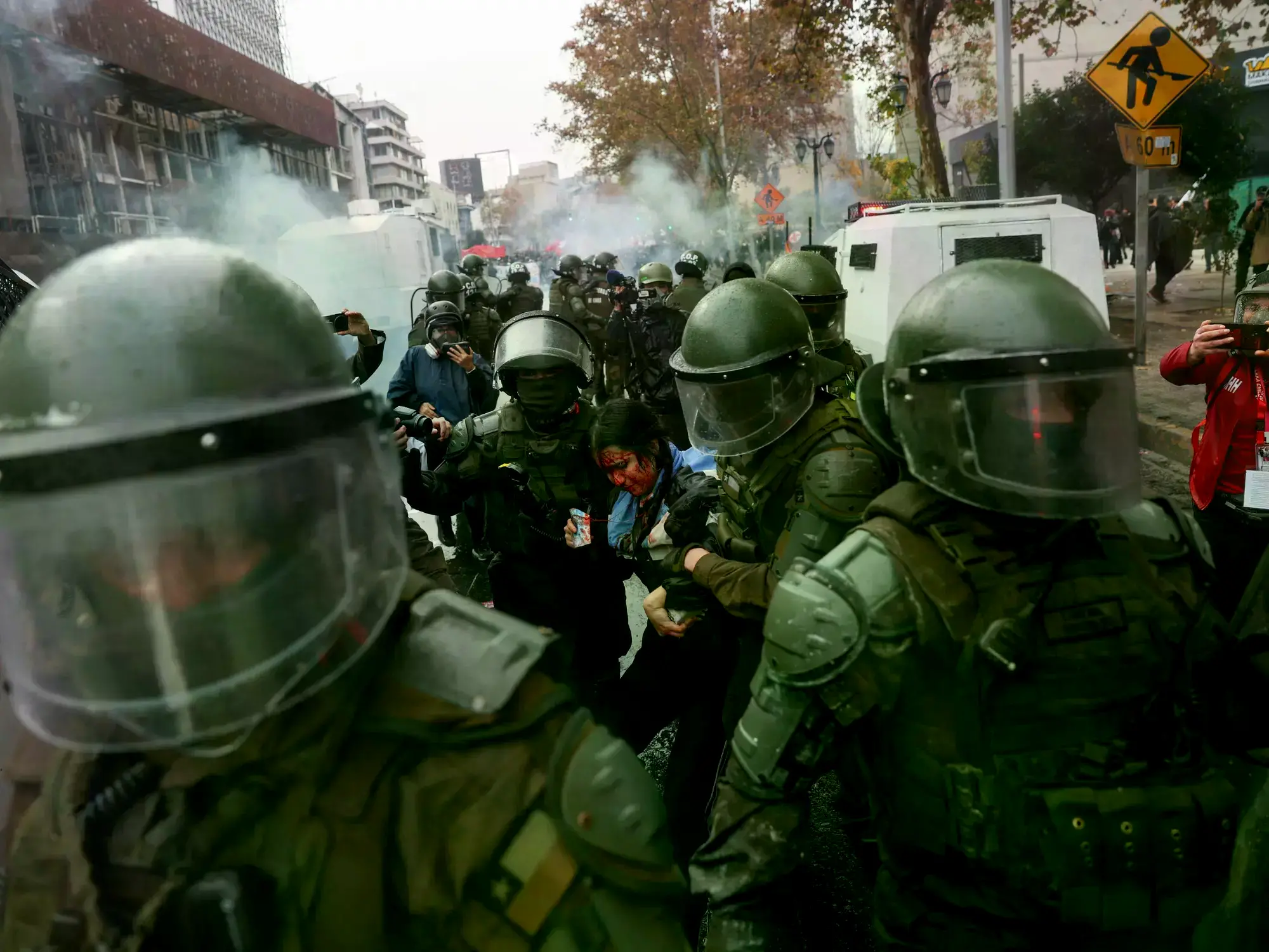 Una manifestante sangra mientras es detenida por la policía antidisturbios durante una protesta en Santiago.