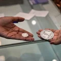 Una vendedora muestra una moneda de plata a un cliente durante Dhanteras, día propicio para comprar metales preciosos.