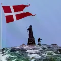 Un hombre camina mientras la bandera danesa ondea junto a la estatua de Hans Egede en Nuuk, Groenlandia.