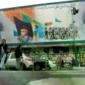 Iraníes caminan junto a un mural que muestra a Ali Jamenei y a Ruhollah Jomeini.
