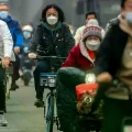Vagabundos con mascarillas circulan en bicicleta por una calle del distrito financiero central de Pekín.