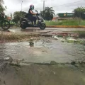 Agua maloliente que rebalsa de una alcantarilla se mezcla con agua de lluvia en una vía.