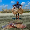 Un pescador sostiene dos rayas de su captura.