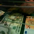 Una cajera cambia un billete de 50€ por dólares estadounidenses en una casa de cambio.