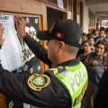 Un policía pega un cartel afuera de un aula de votaciones en el colegio Señor de los Milagros en Lurín.
