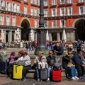 Turistas sentados en un banco público en la Plaza Mayor, en el centro de Madrid, España.