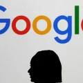 Una mujer pasa junto a una pantalla gigante con el logotipo de Google durante la cumbre AI Action en París.