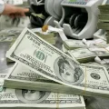 Un empleado de banco surcoreano trabaja junto a fajos de billetes estadounidenses en la sede del Korea Exchange Bank en Seúl