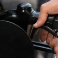 Una persona asegura la boquilla de combustible mientras llena el tanque de su vehículo en una gasolinera el martes 12 de mayo