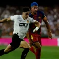 El delantero del Valencia Diego López pelea un balón con Ronald Araújo.